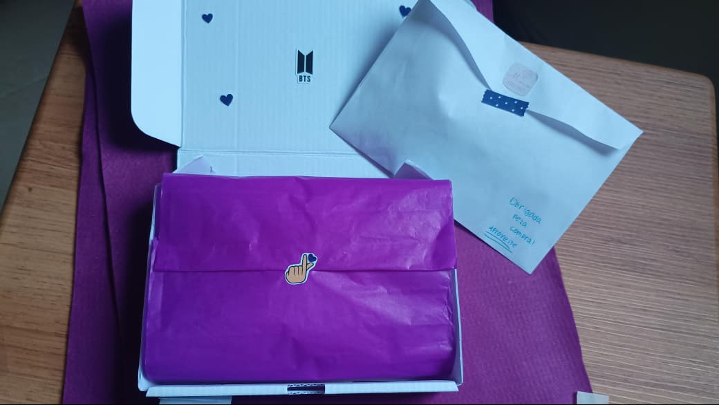 Caixa aberta, com papel de seda roxo e adesivos de decoração